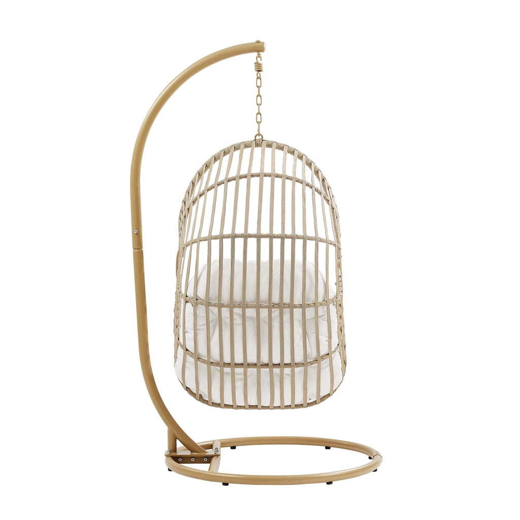 Outdoor hanging wicker swing chair with white cushion and tall rounded back basket.