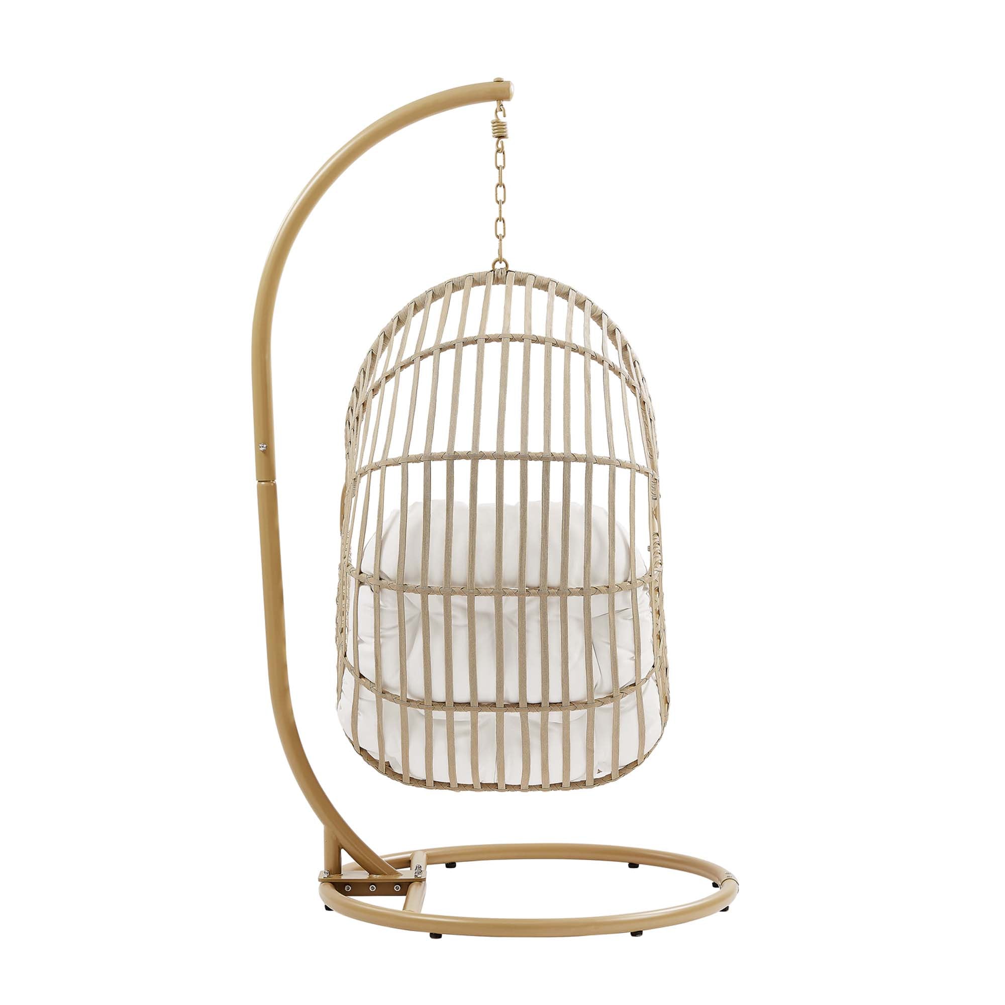 Outdoor hanging wicker swing chair with white cushion and tall rounded back basket.