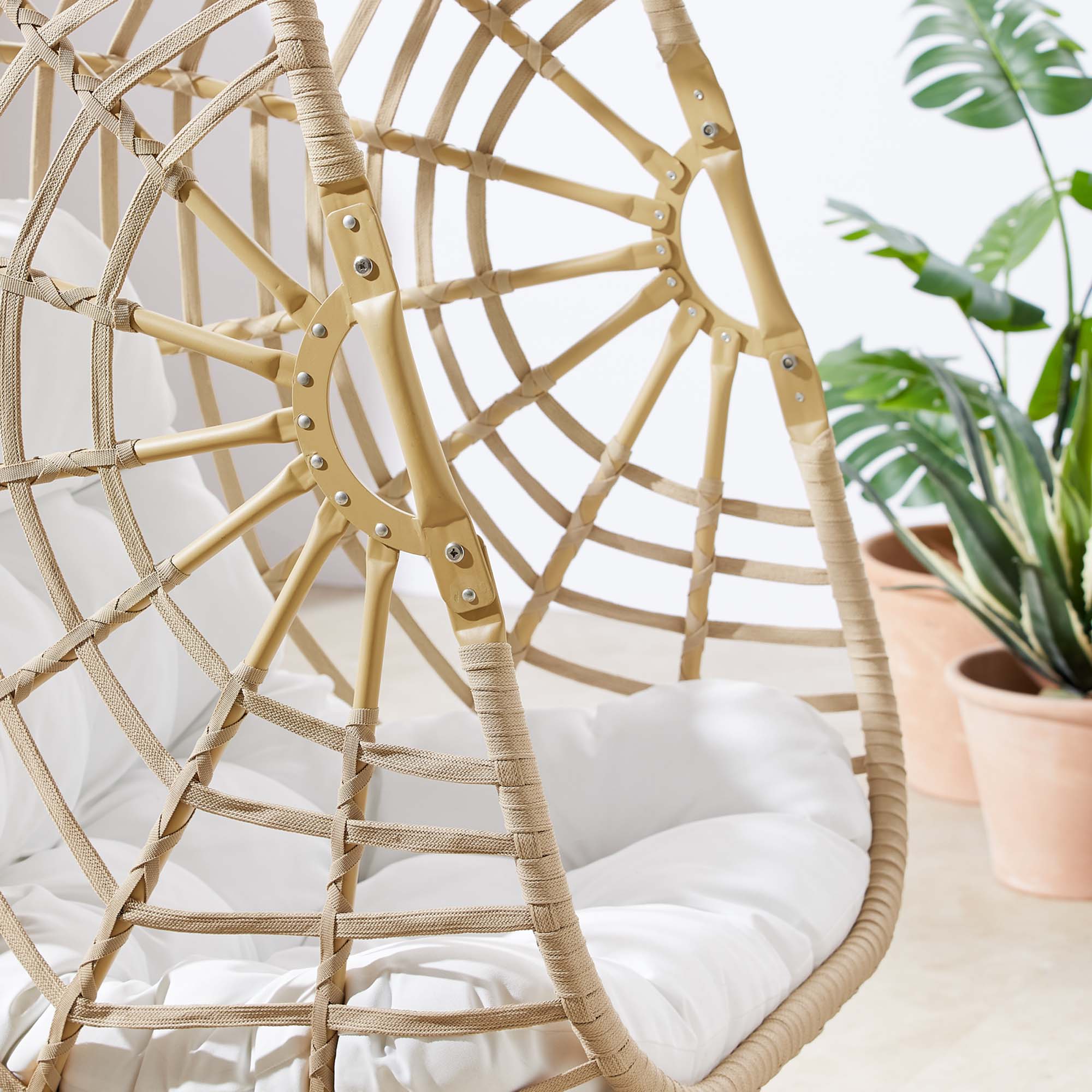 Wicker swing chair seat close-up with white cushion and textured rattan weave.