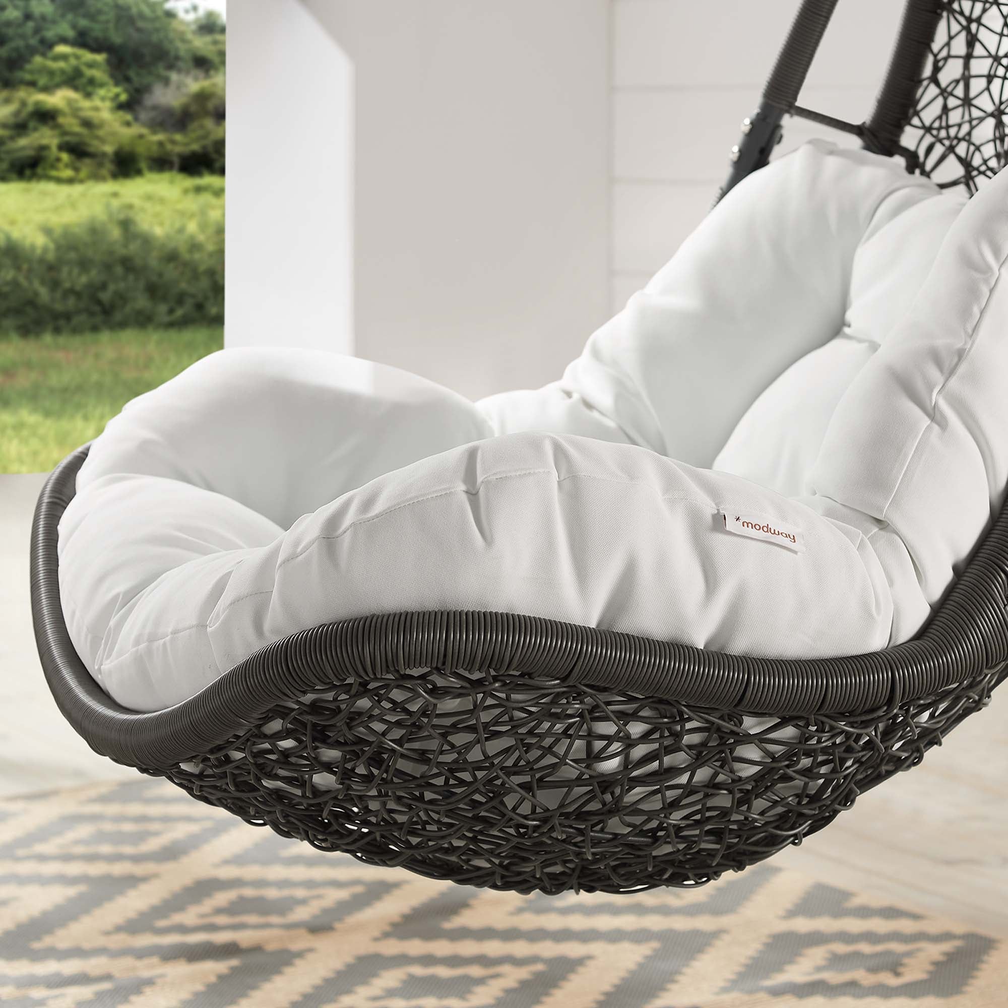 Outdoor hanging swing chair cushion with plush white padding and black woven edge