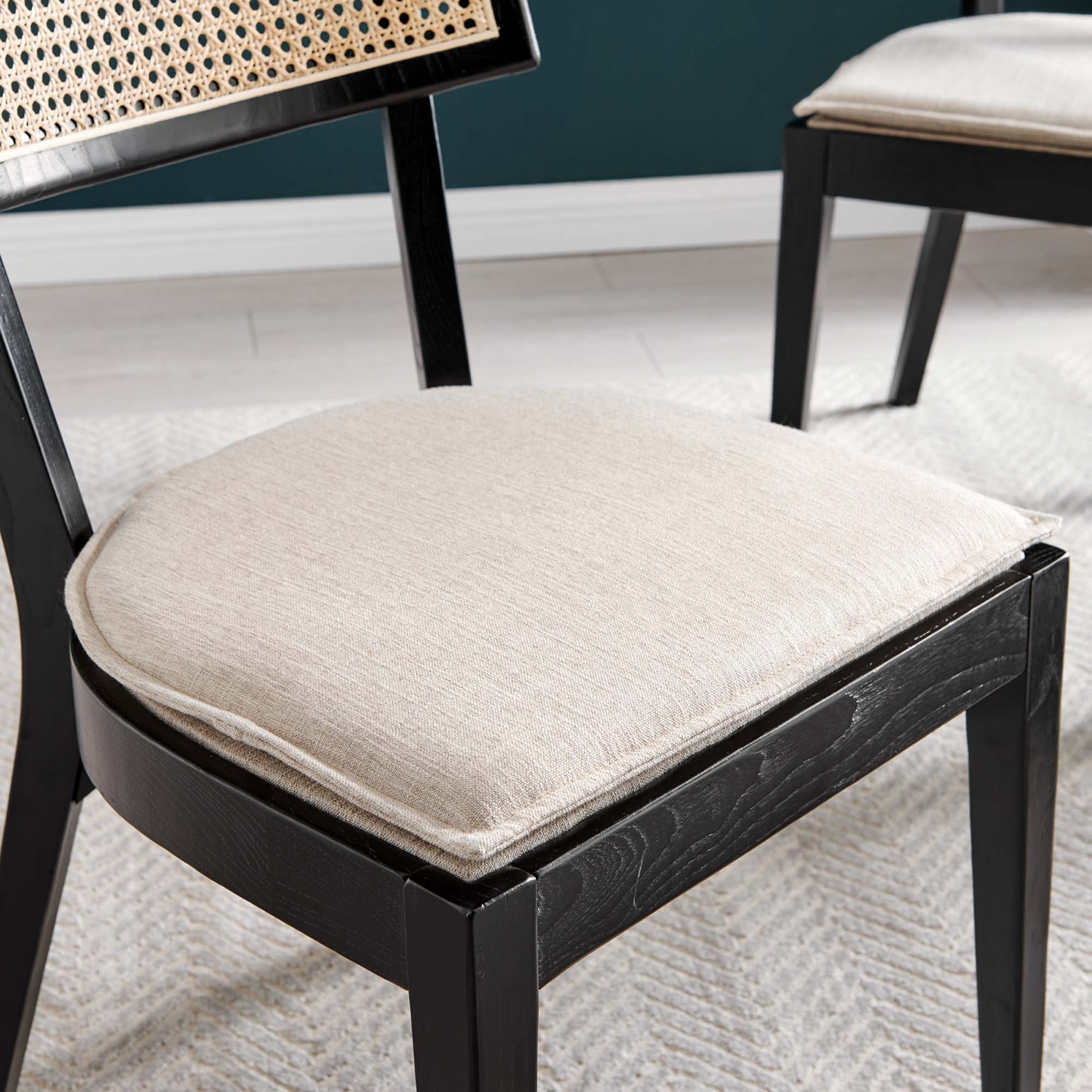 Beige upholstered seat on black wood dining chair with woven rattan cane backrest