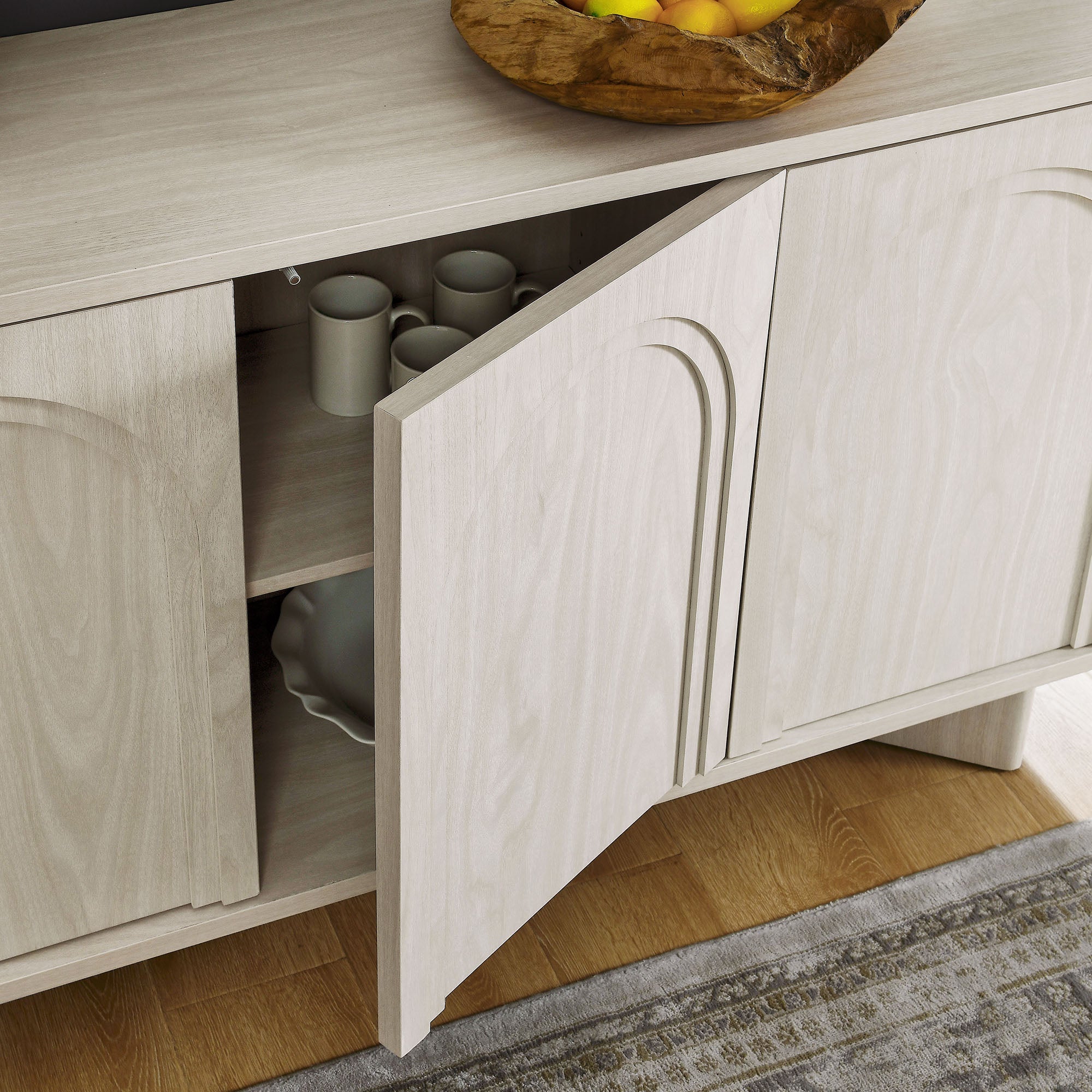 Arched 3-door sideboard storage cabinet in white wash with door open to reveal adjustable interior shelves.