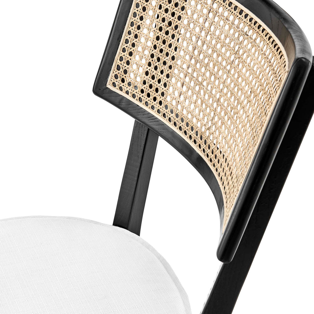 Curved woven rattan cane backrest on black wood dining chair with beige upholstered seat