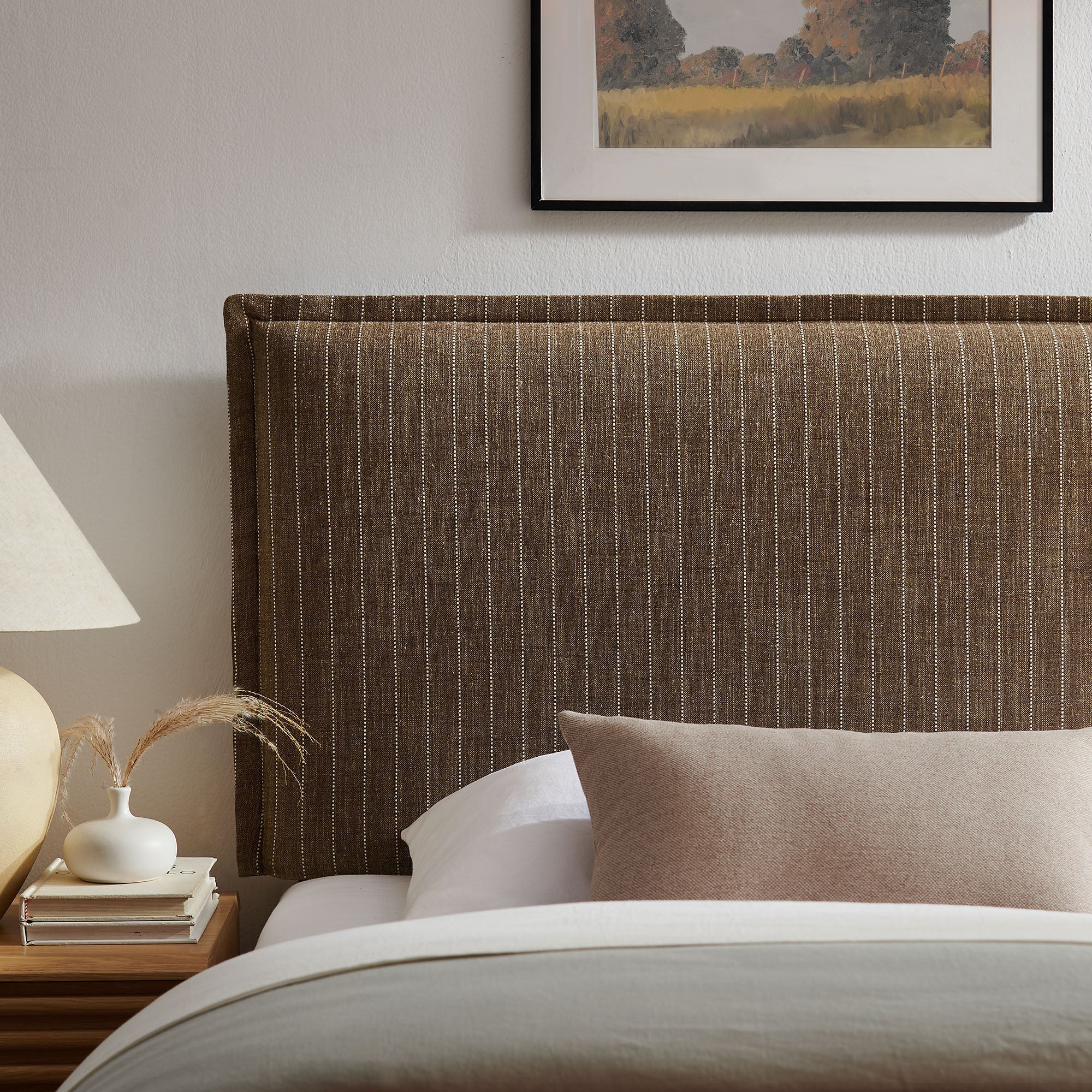 Striped upholstered headboard in brown pinstripe fabric with dark legs and padded frame.